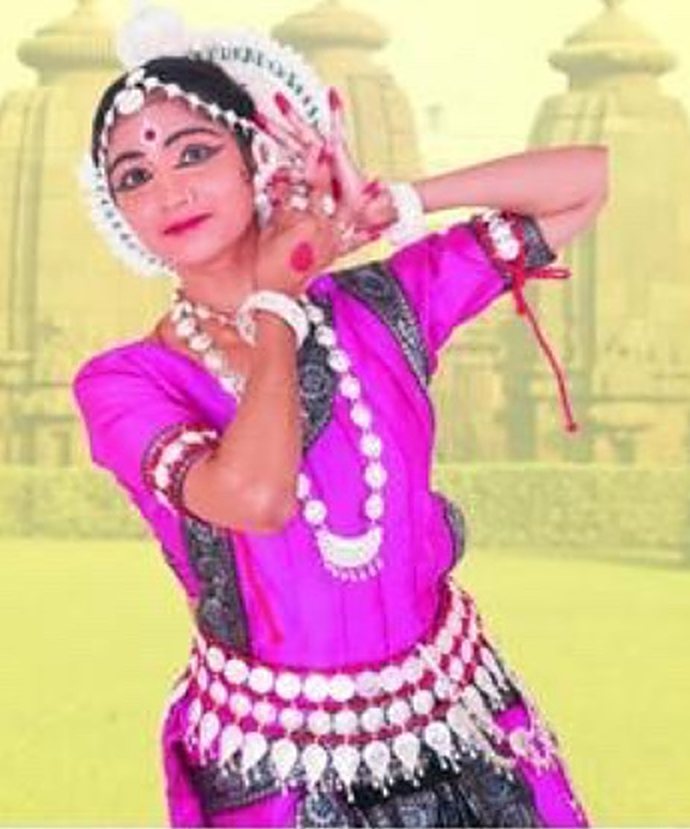 Purnima performing an Odissi pose in a magenta costume before temple spires